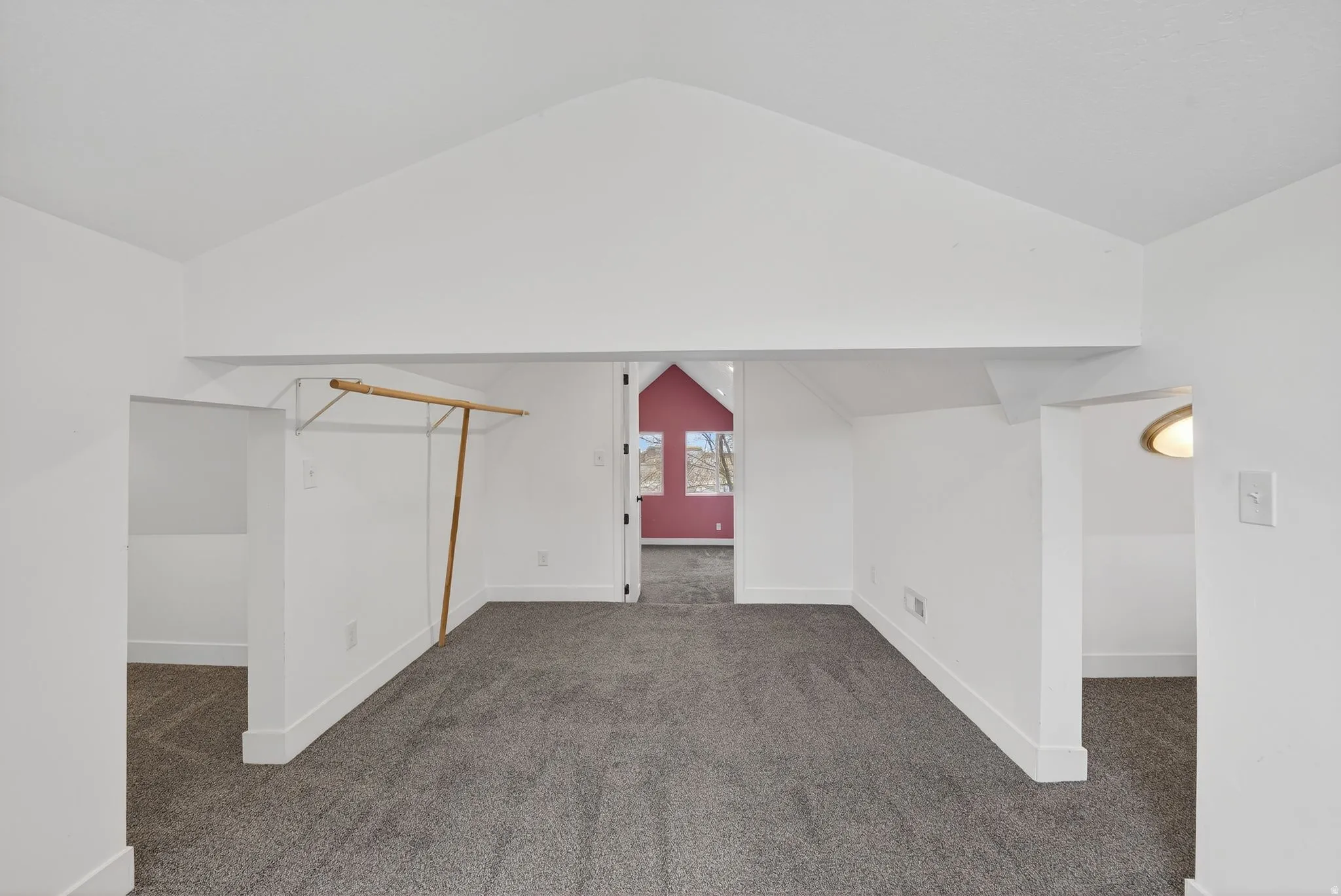 Additional living space with dark carpet and baseboards