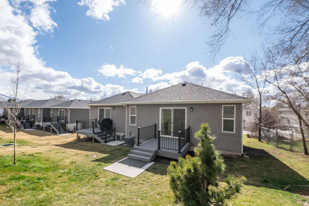 Back of property with a deck, a shingled roof, and stucco siding