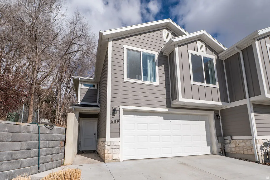 View of front of home with stone siding, an attached garage, board and batten siding, and concrete driveway