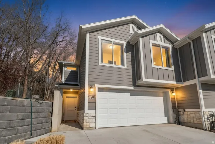View of front of house with stone siding, a garage, board and batten siding, and driveway