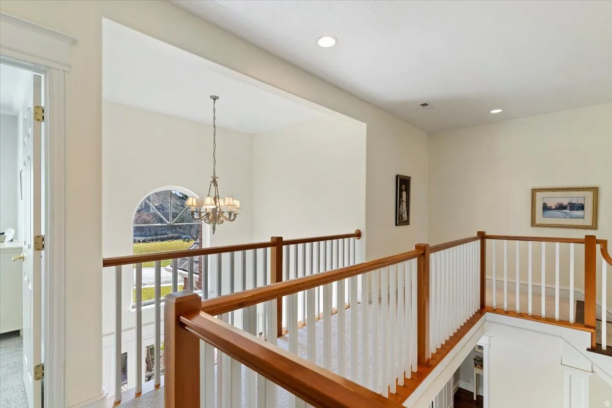 Hallway with an upstairs landing and a chandelier