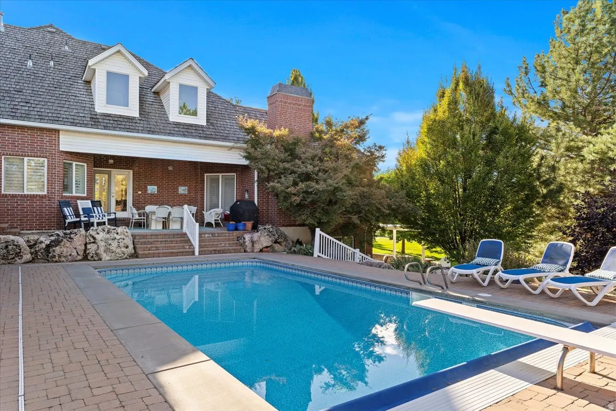 Outdoor pool with a patio area, a diving board, and grilling area