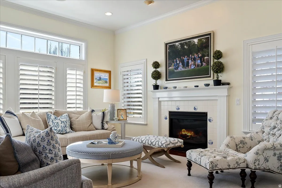 Carpeted living area featuring crown molding, a tiled fireplace, and recessed lighting
