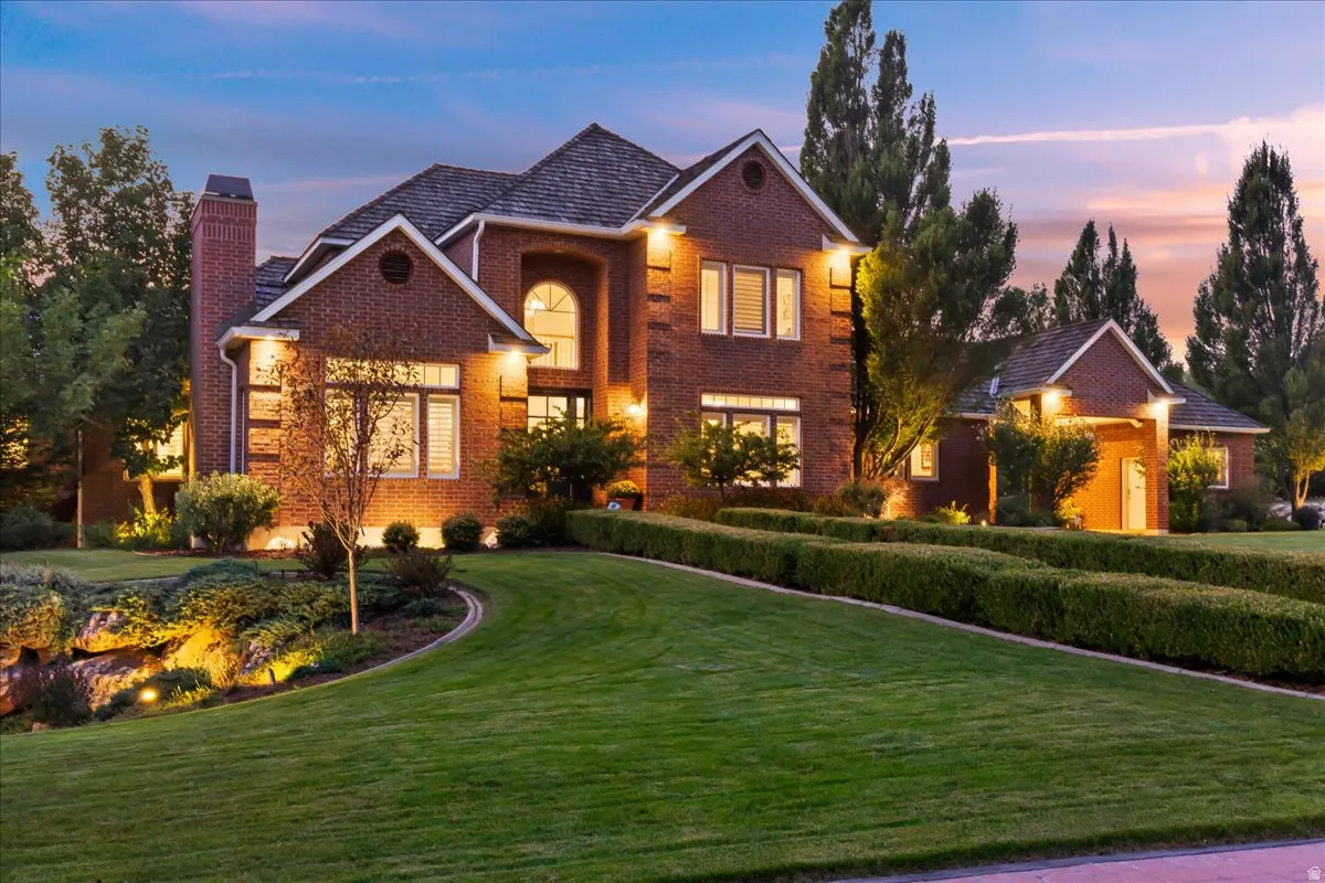 Traditional-style home with a front lawn, a chimney, and brick siding