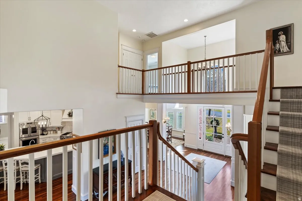 Stairs featuring a chandelier, a high ceiling, and wood finished floors