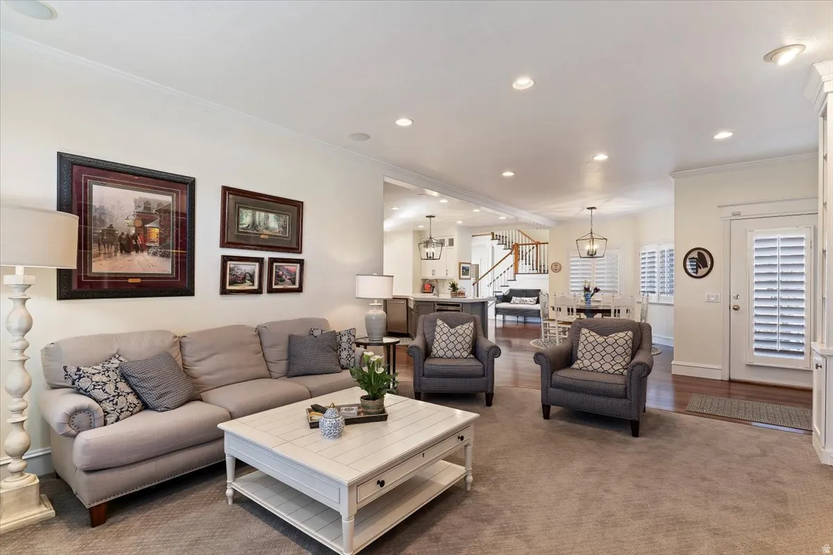Carpeted living room with ornamental molding and suspended lighting