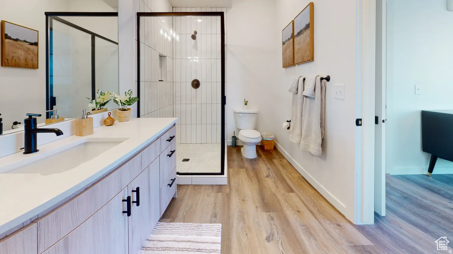 Bathroom with vanity, a shower stall, and light wood-style flooring