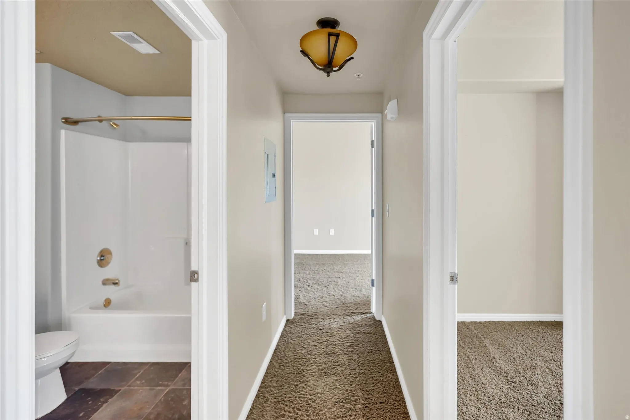 Corridor featuring dark carpet and baseboards