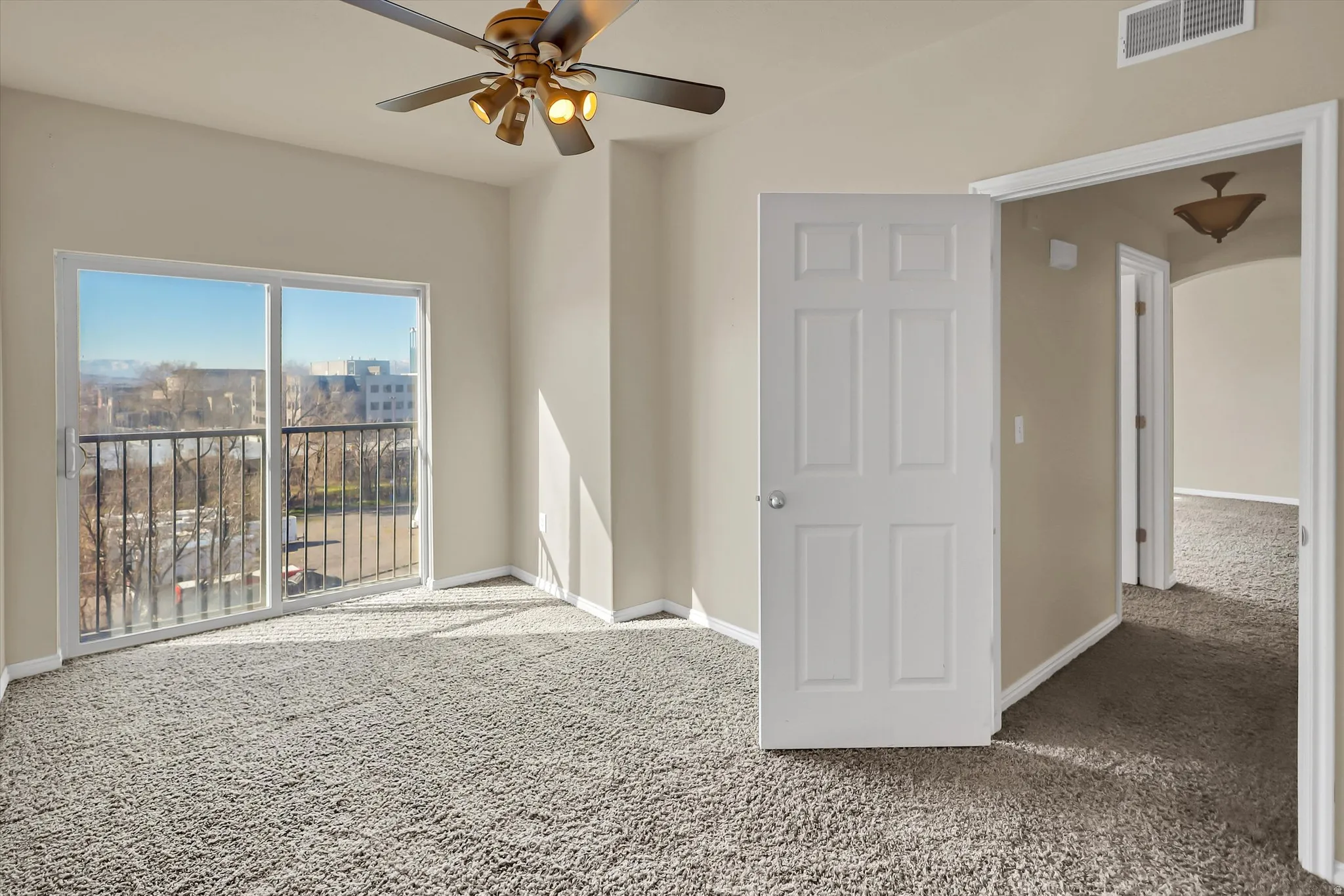 Unfurnished room featuring carpet, a ceiling fan, and arched walkways