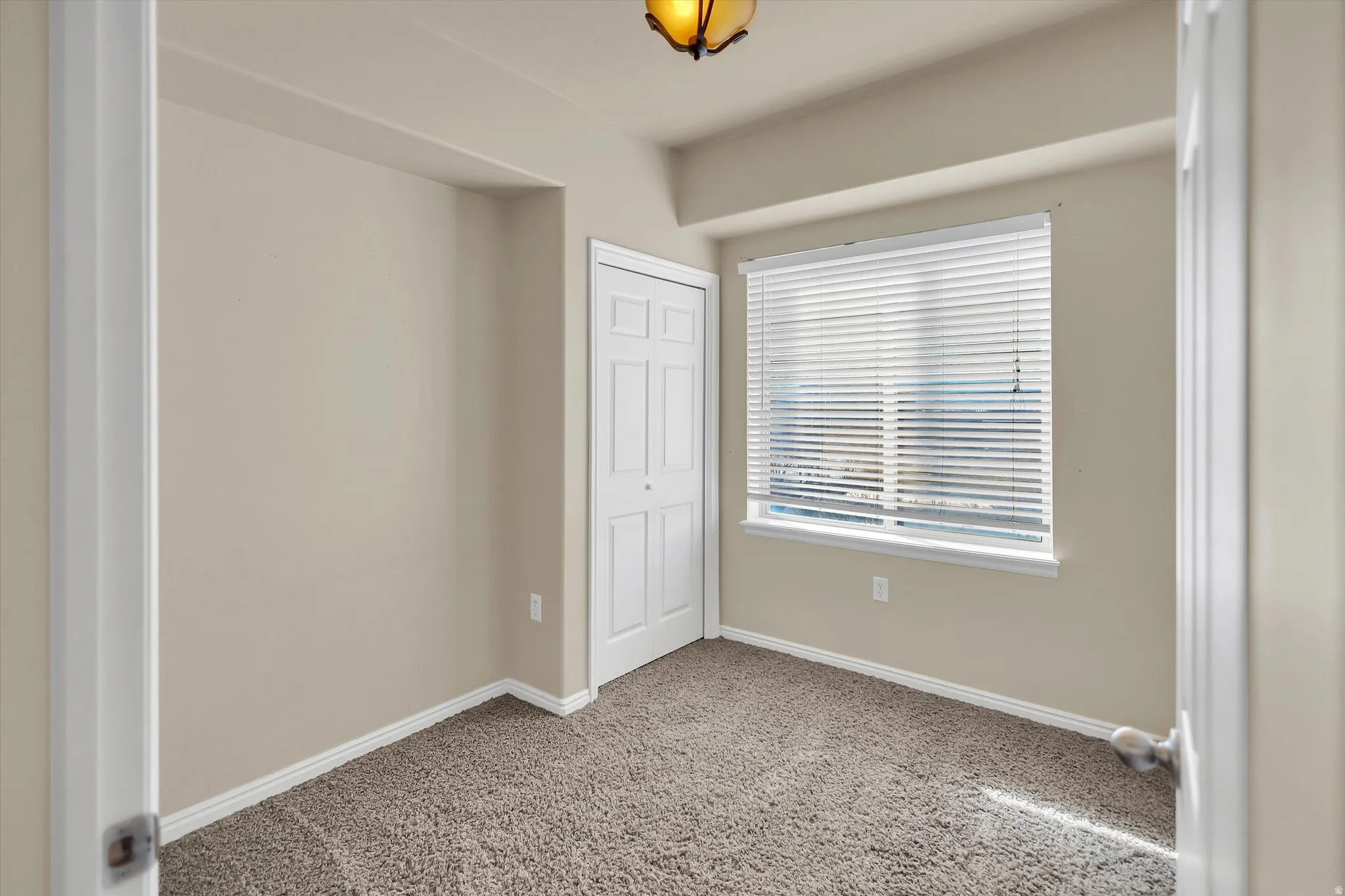 Unfurnished bedroom featuring light carpet and a closet