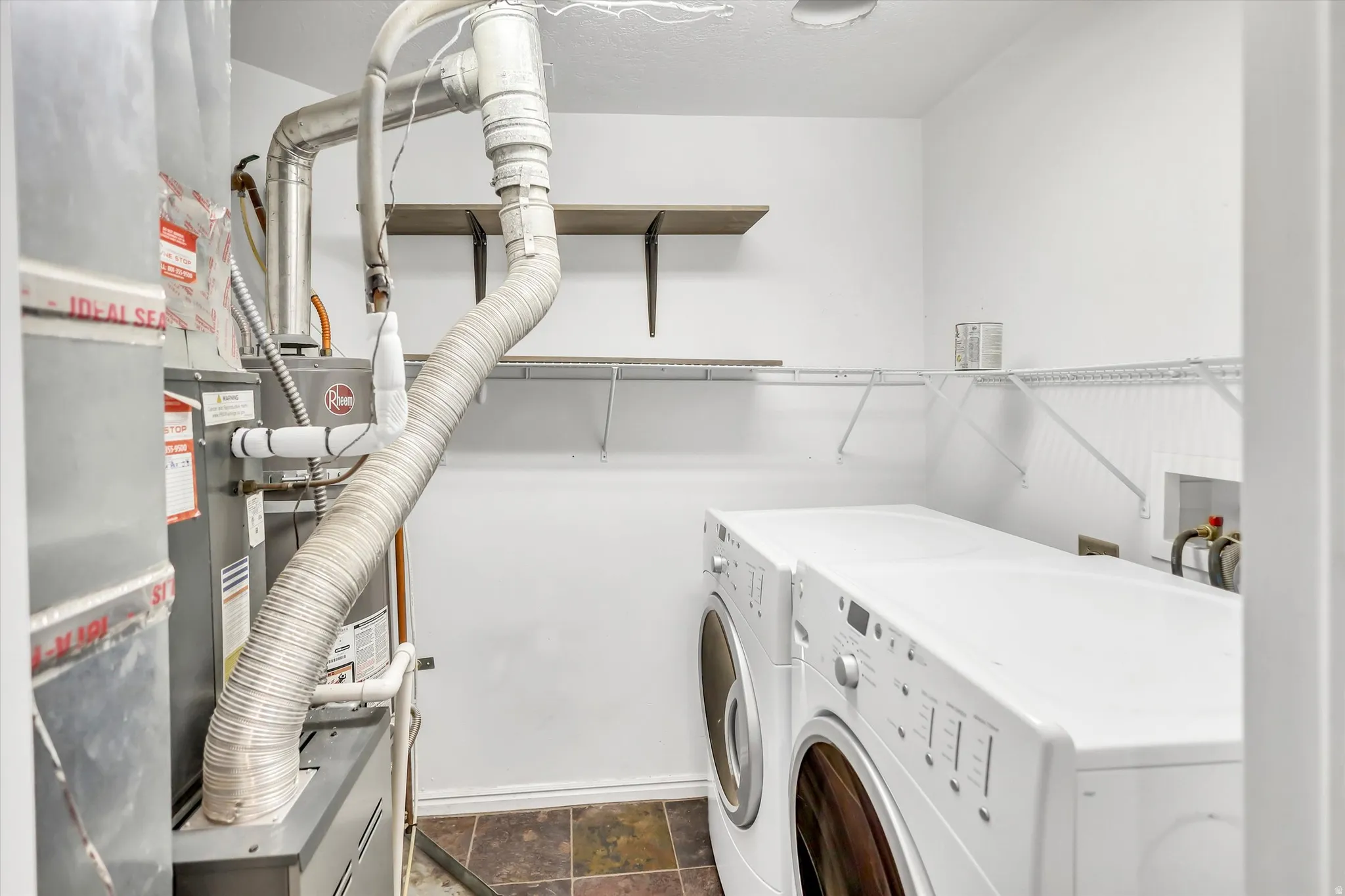 Laundry area featuring stone finish floors and washing machine and clothes dryer