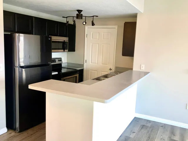 Kitchen featuring black cabinetry, stainless steel microwave, black electric range, and a two-basin stainless steel sink