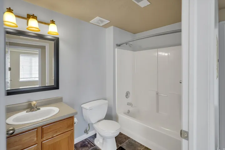 Bathroom featuring vanity, bathing tub / shower combination, and dark tile patterned floors