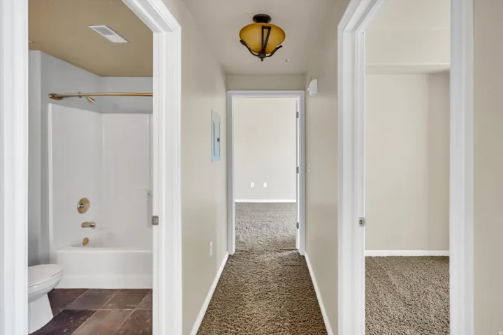 Corridor featuring dark carpet and baseboards