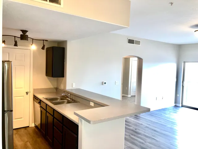 Kitchen with dark wood cabinetry, stainless steel double sink, and light-toned countertops