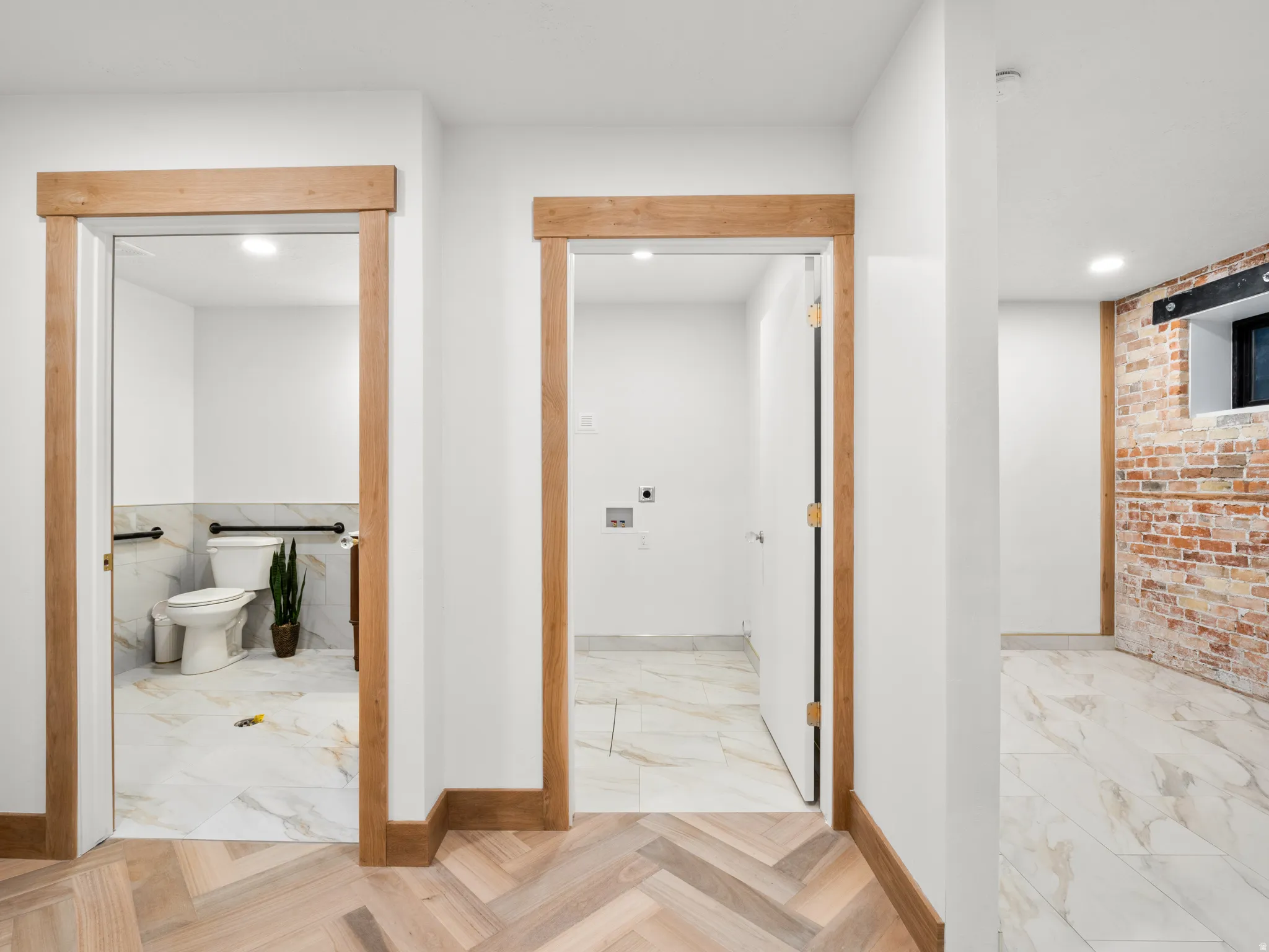 Corridor with recessed lighting, light marble finish flooring, and brick wall
