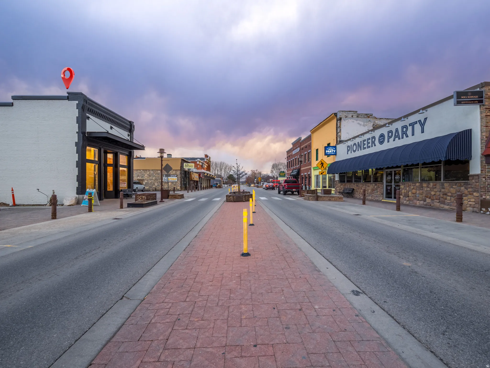 View of asphalt street featuring sidewalks, curbs, and street lighting