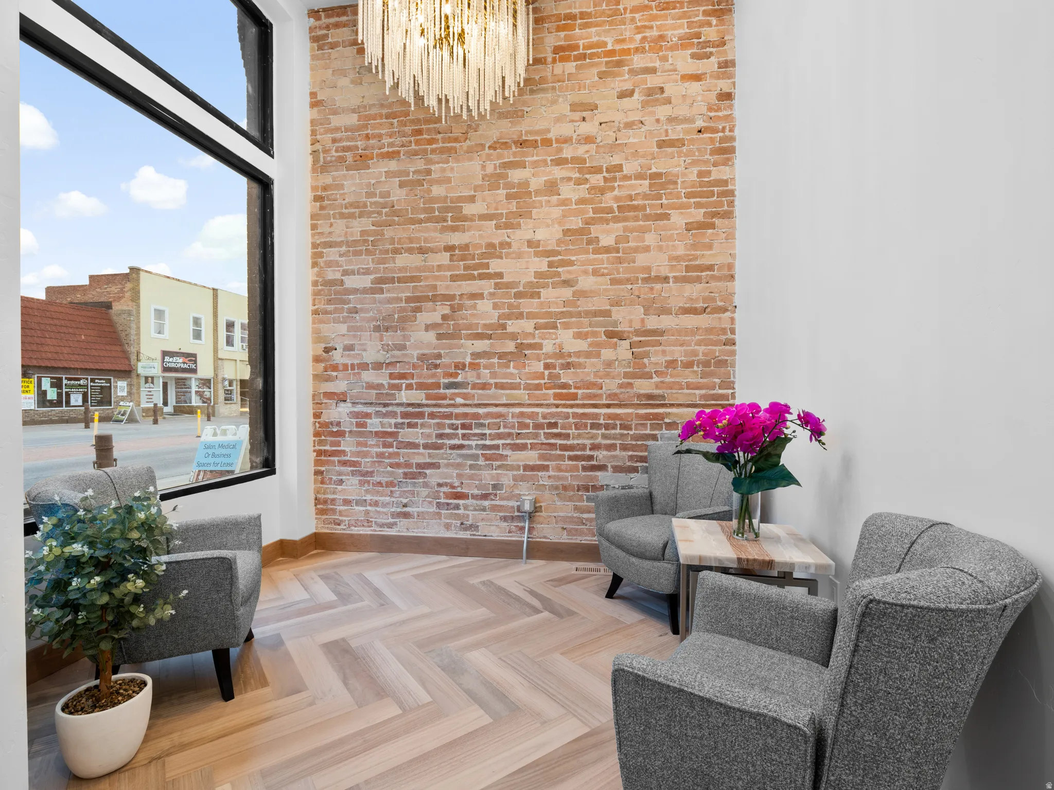 Sitting room with brick wall, a chandelier, and a high ceiling
