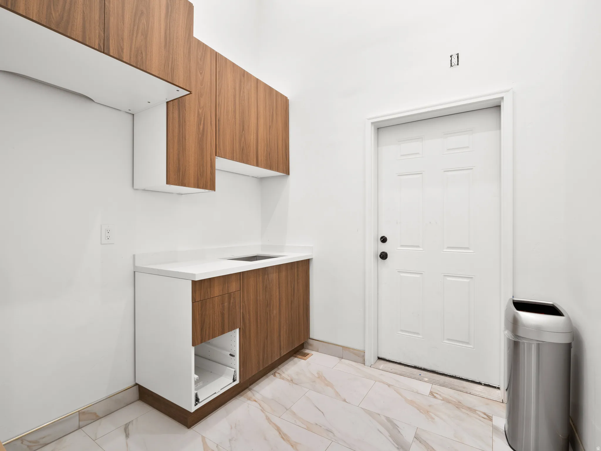 Laundry area featuring light marble finish floors and baseboards