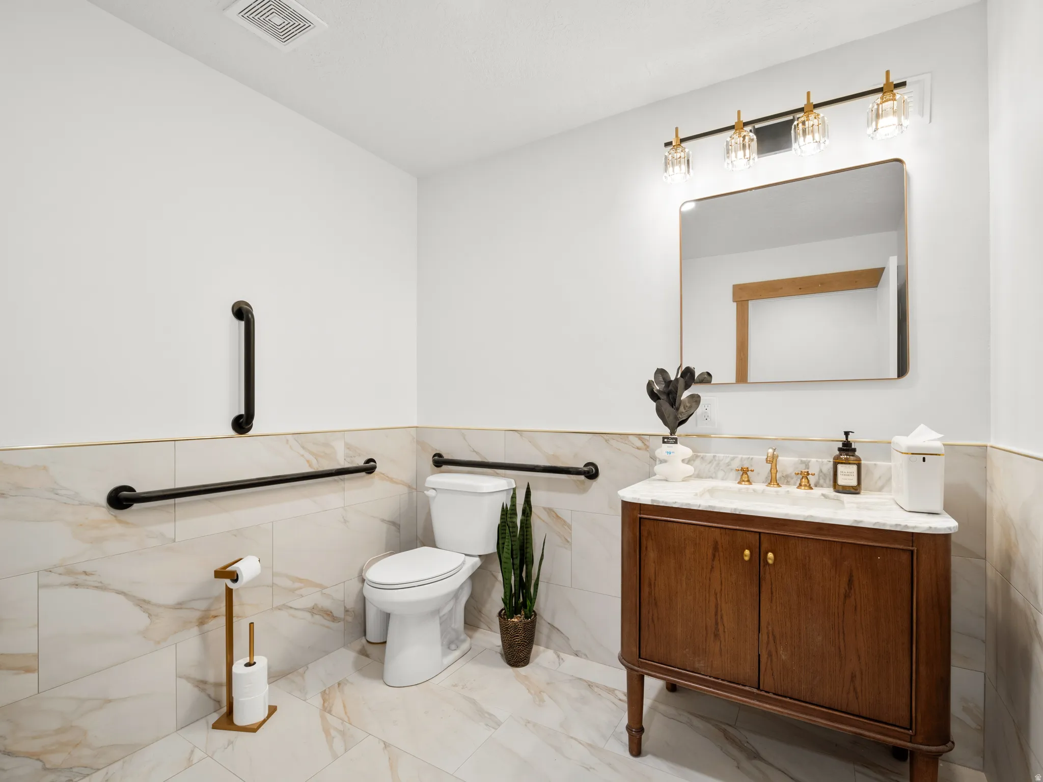 Bathroom with vanity, tile walls, and a wainscoted wall