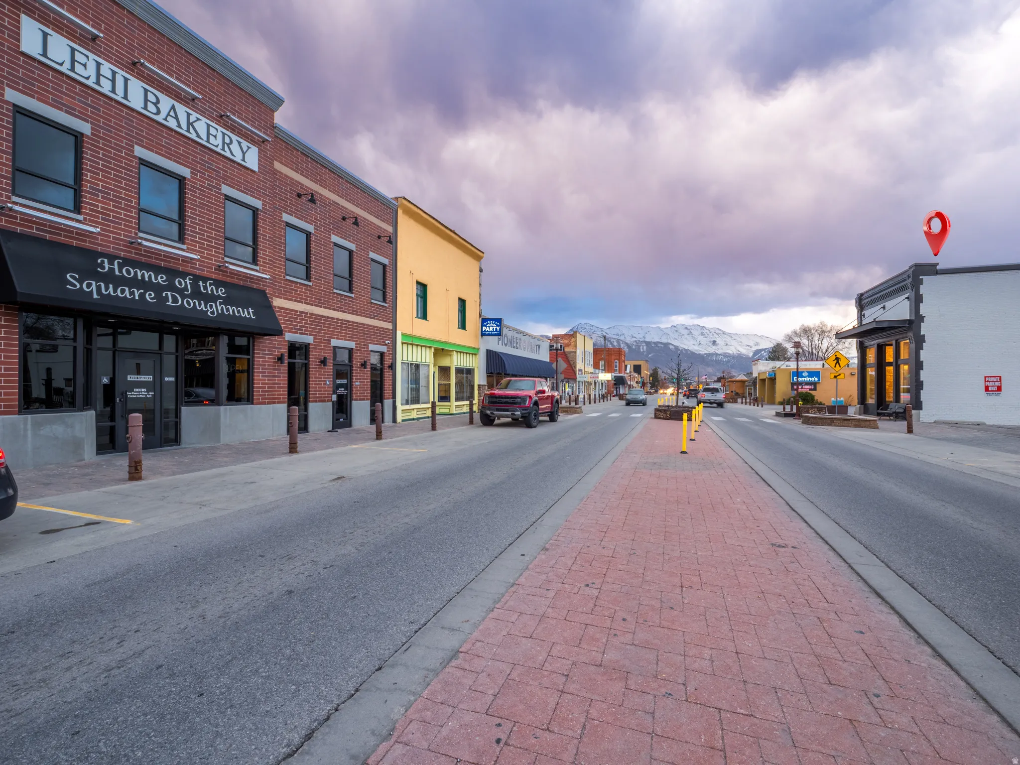 View of asphalt street with sidewalks, a mountain view, street lighting, and curbs