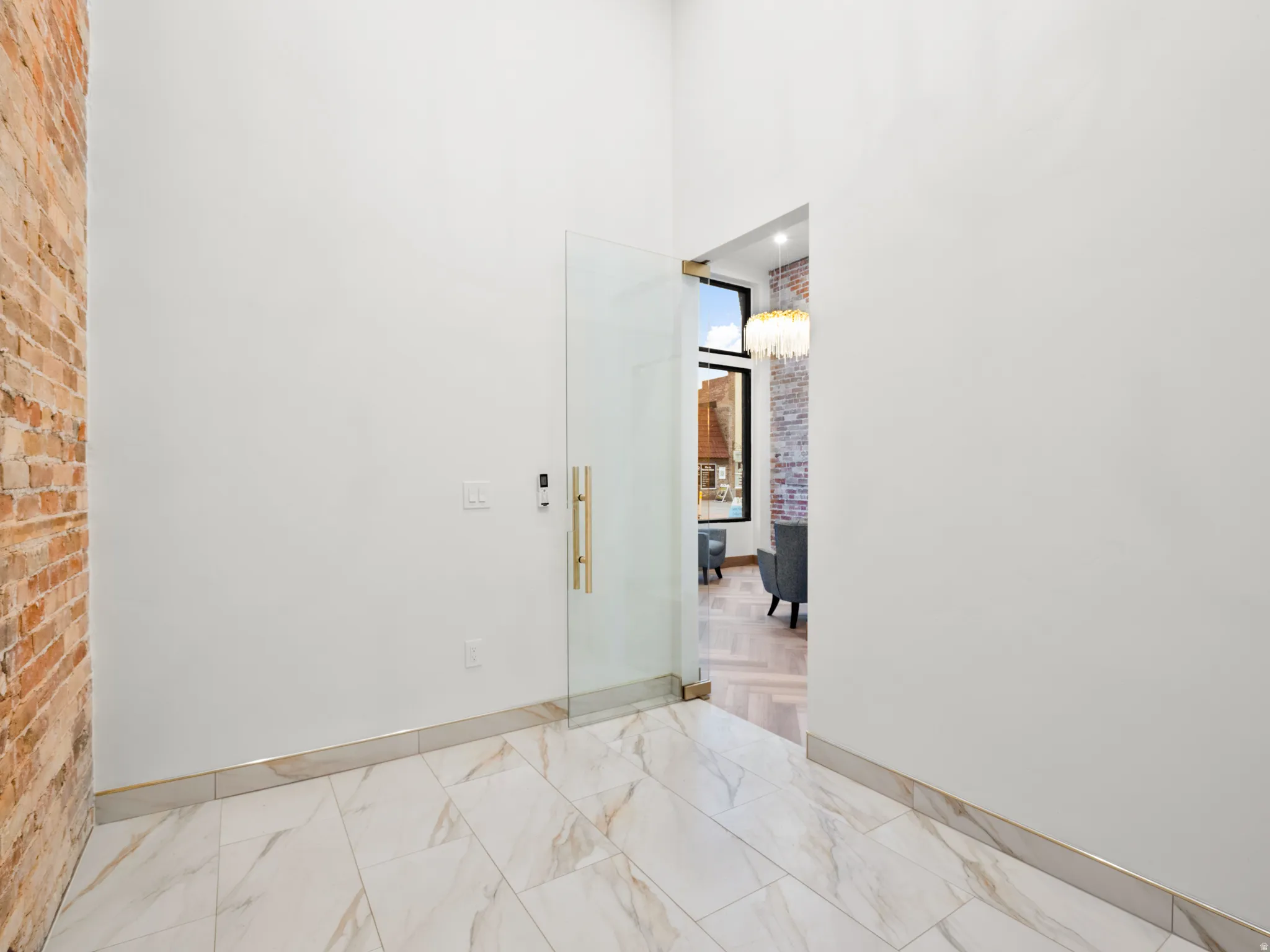 Spare room featuring a high ceiling, suspended lighting, and brick wall