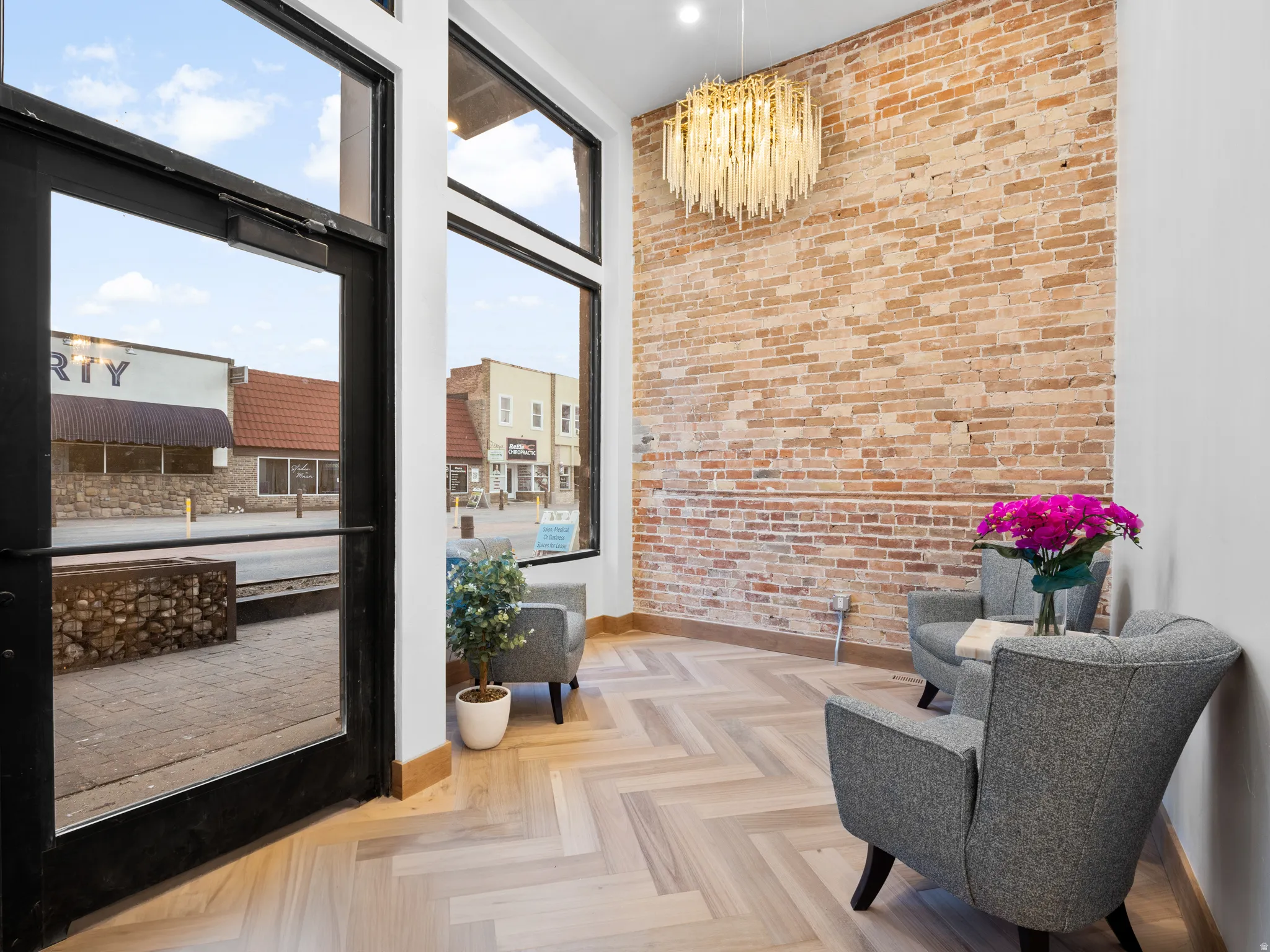 Doorway to outside featuring brick wall, parquet floors, a high ceiling, and hanging lights