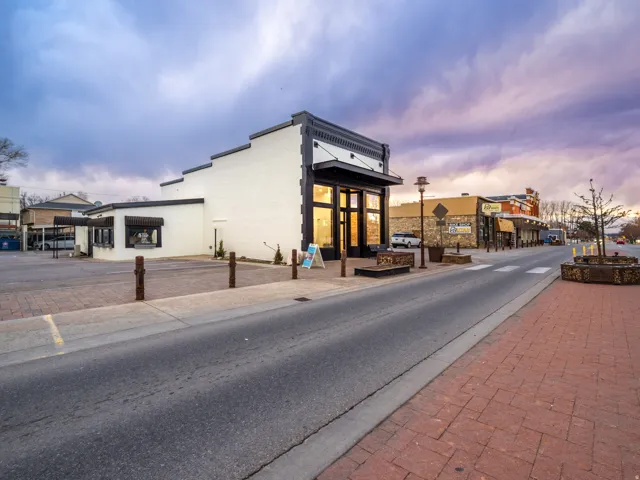 View of asphalt street featuring sidewalks, curbs, and street lights