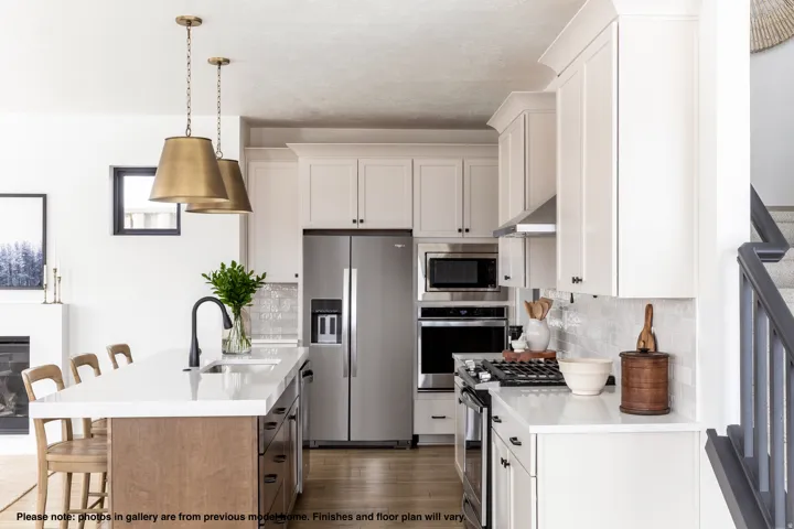 Dual tone kitchen featuring a breakfast bar area, stainless steel appliances, light stone countertops, backsplash, and dual tone cabinets