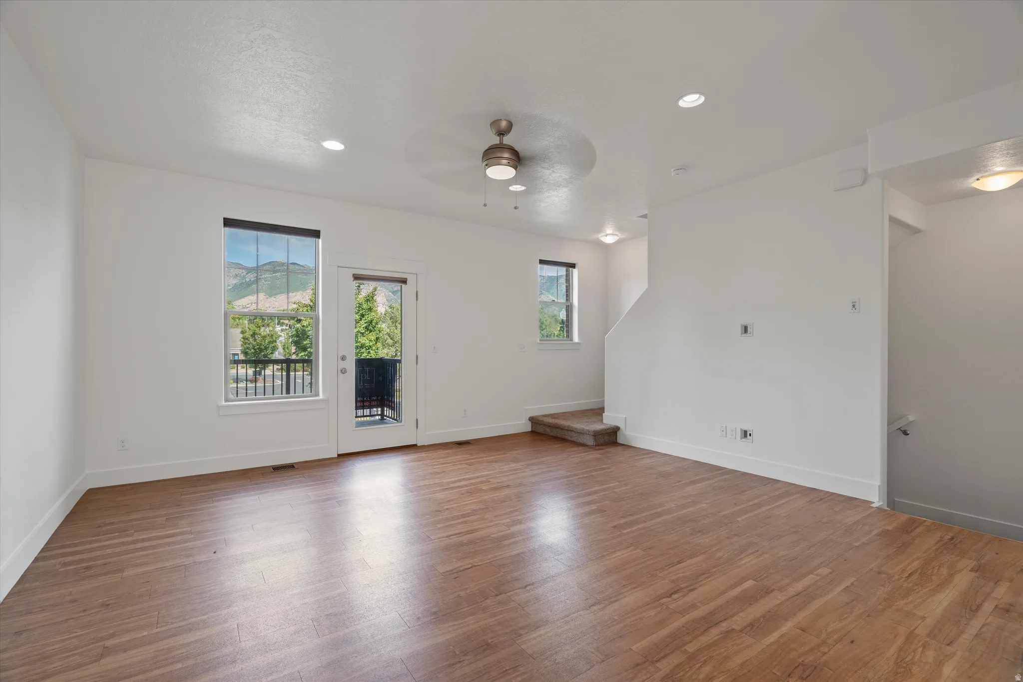 Spacious open-concept room featuring wood-finish flooring, white baseboards, and neutral wall tones