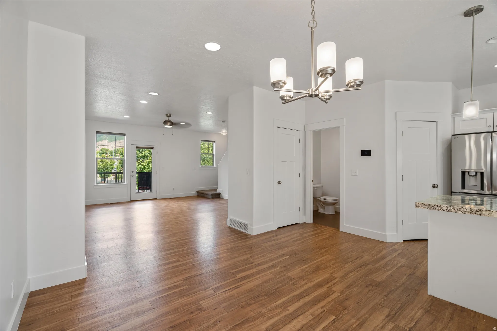 Open concept living space featuring wood-finish flooring, recessed lighting, and a modern chandelier