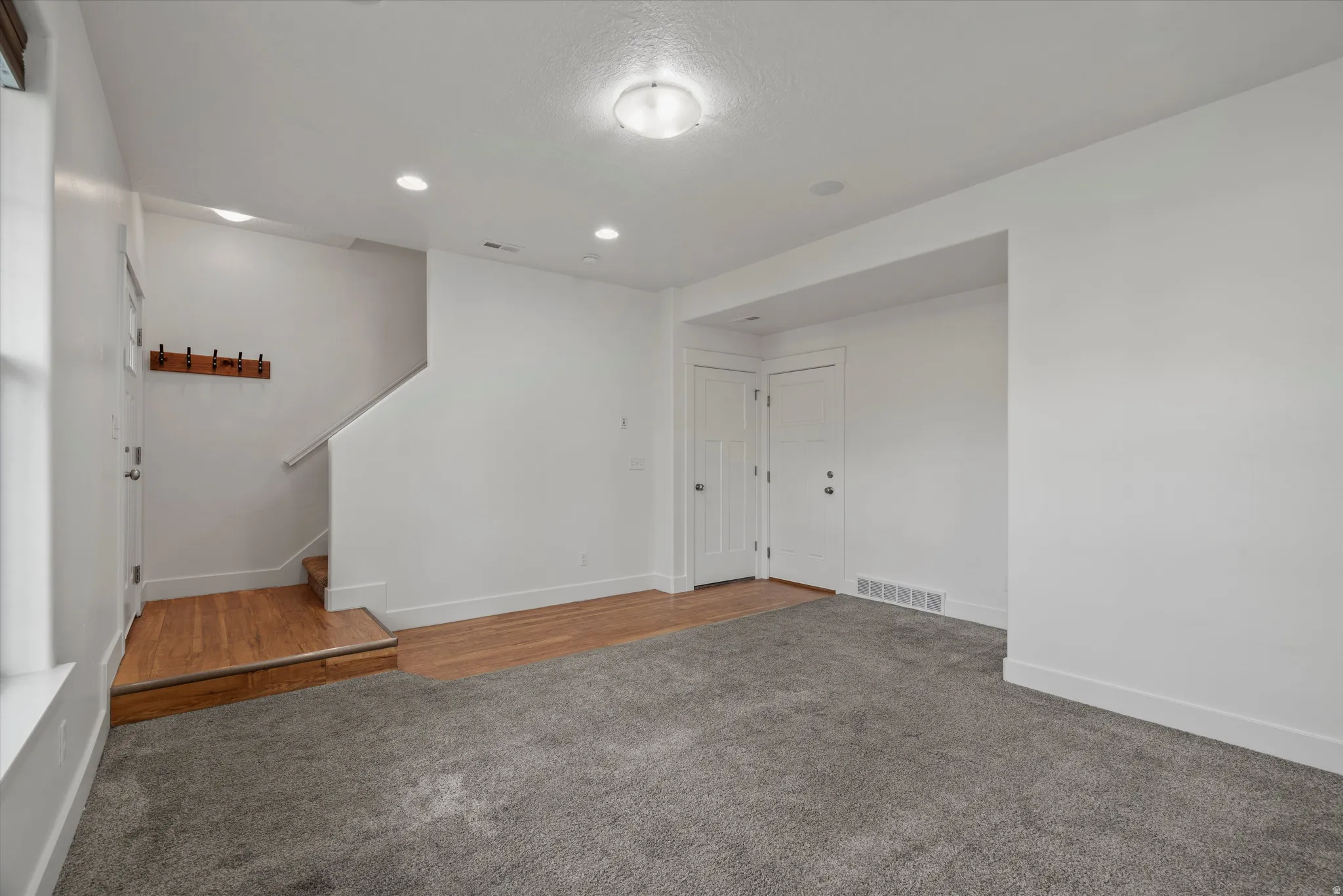 Spacious interior featuring a combination of gray carpet and wood-finish flooring