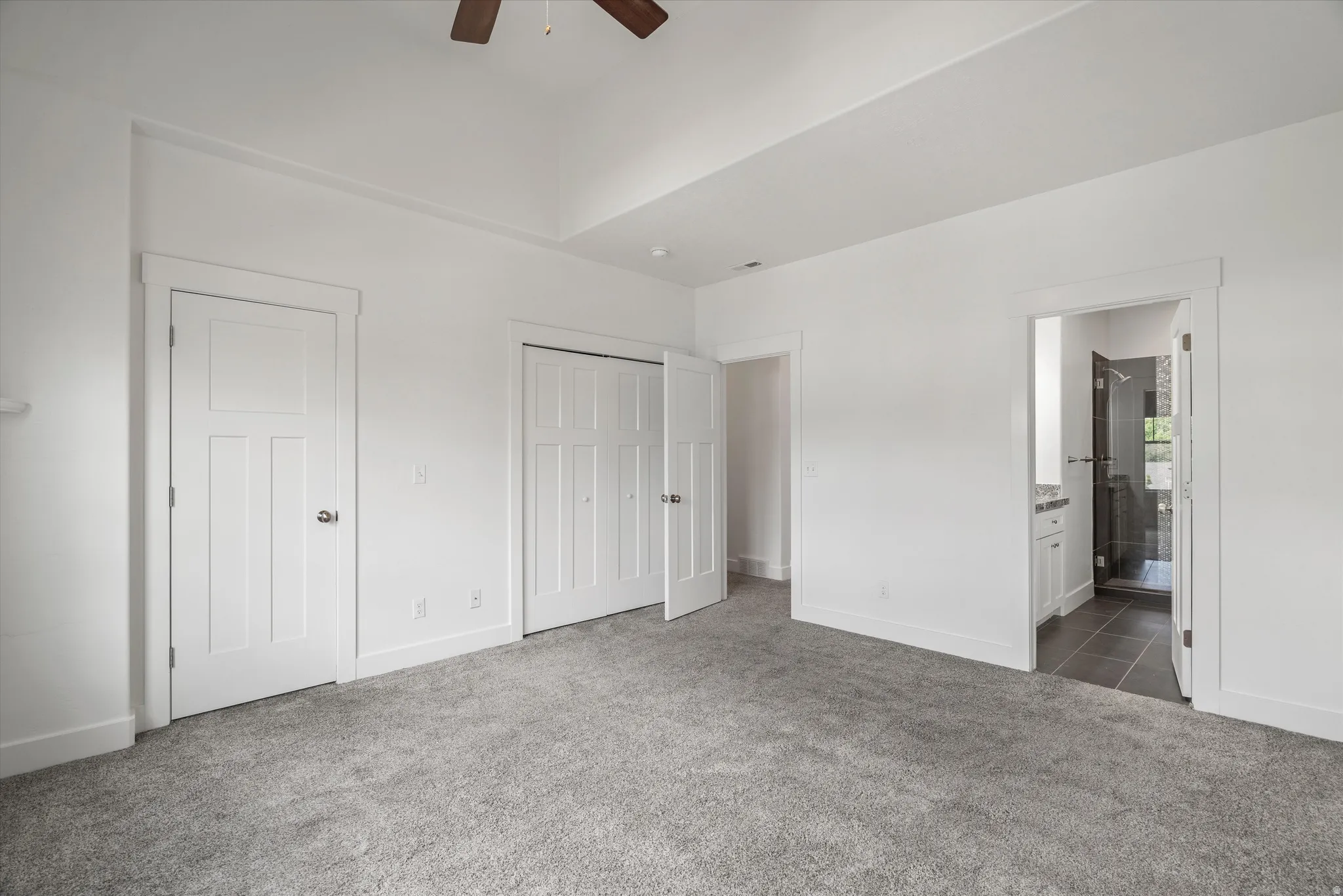 Carpeted interior space with white walls and a vaulted ceiling