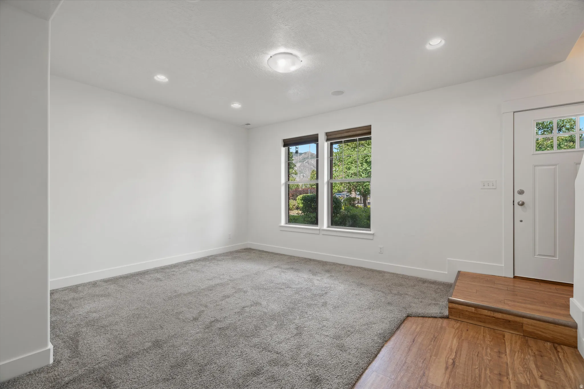 Carpeted living area featuring recessed lighting and a central flush-mount fixture