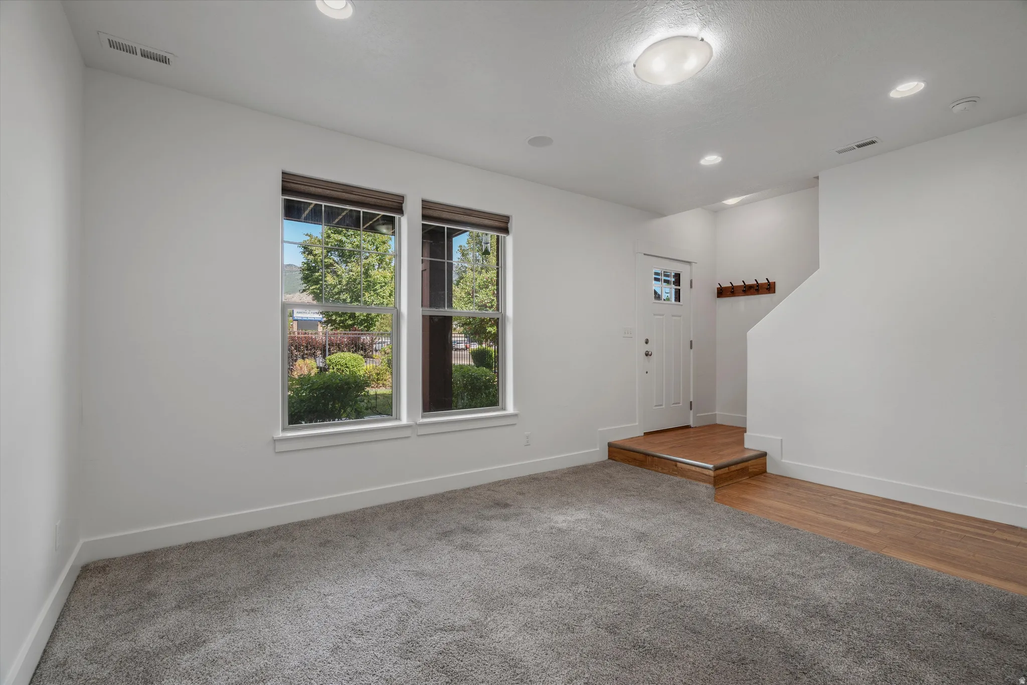 Entryway featuring a white paneled door with glass inserts, wood-finish flooring, and a built-in coat rack