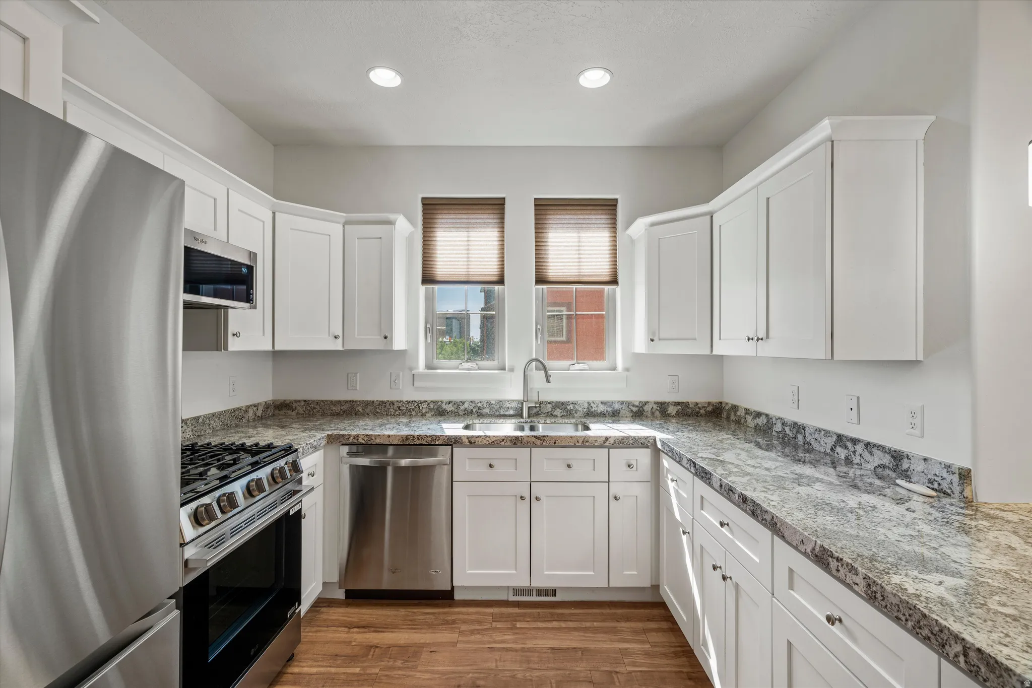 Bright kitchen featuring white shaker cabinetry and wood-finish flooring
