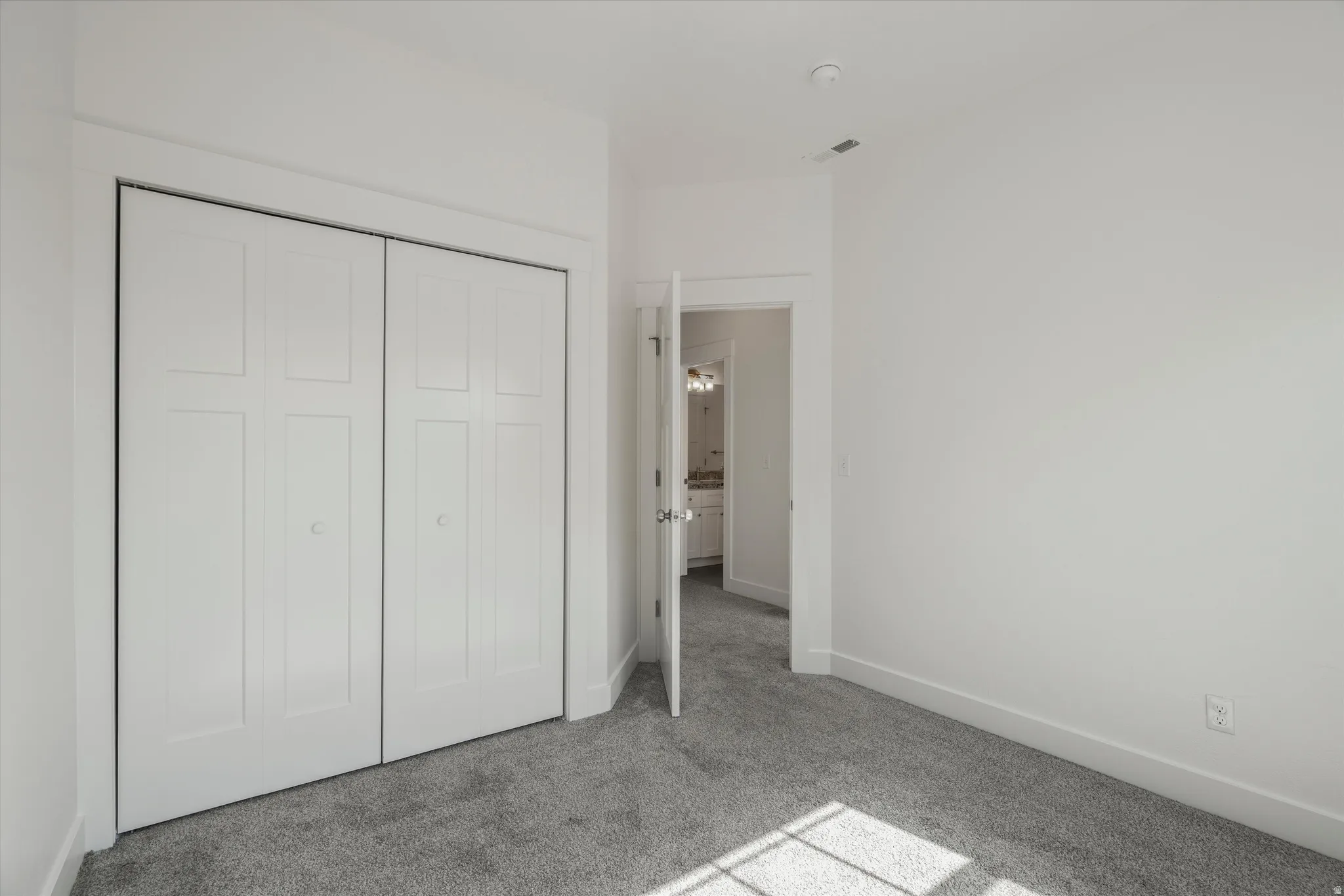 Neutral interior space featuring light gray carpet flooring and white painted walls