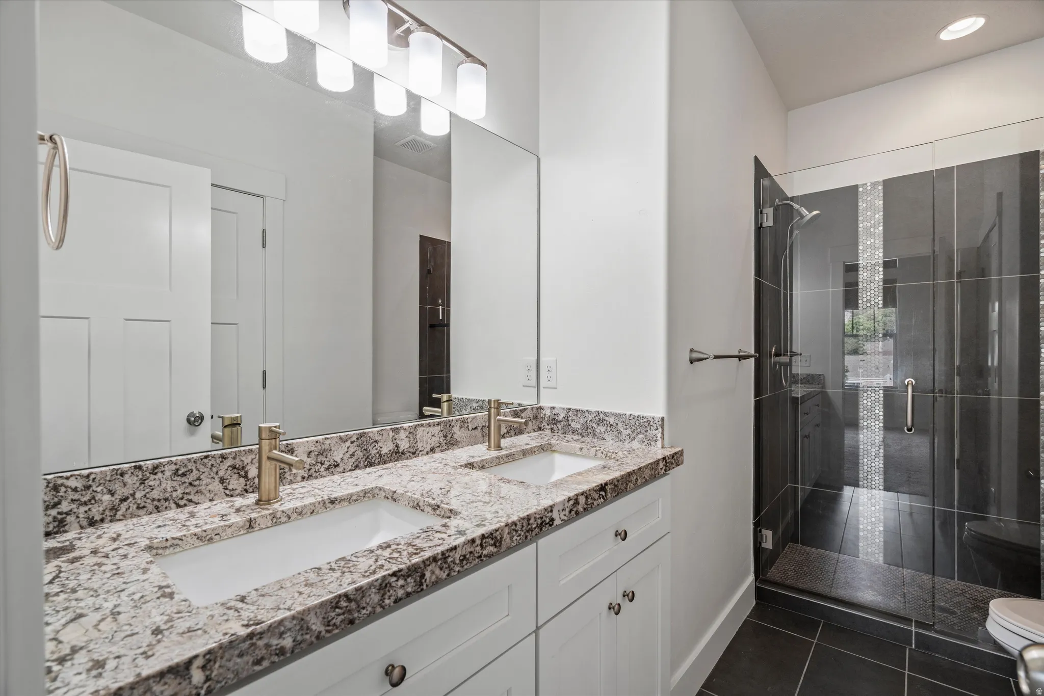 Dual vanity with integrated rectangular sinks, stone-finish countertop, and brushed brass fixtures