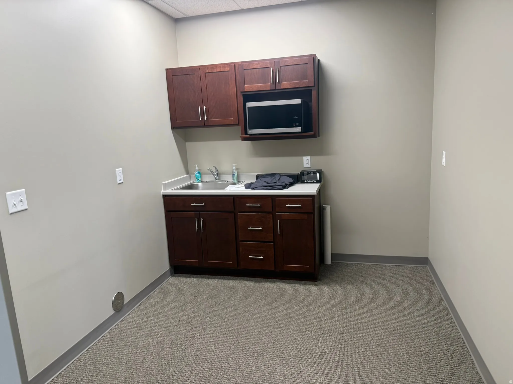 Kitchen with light carpet, light countertops, stainless steel microwave, and dark wood finish cabinetry