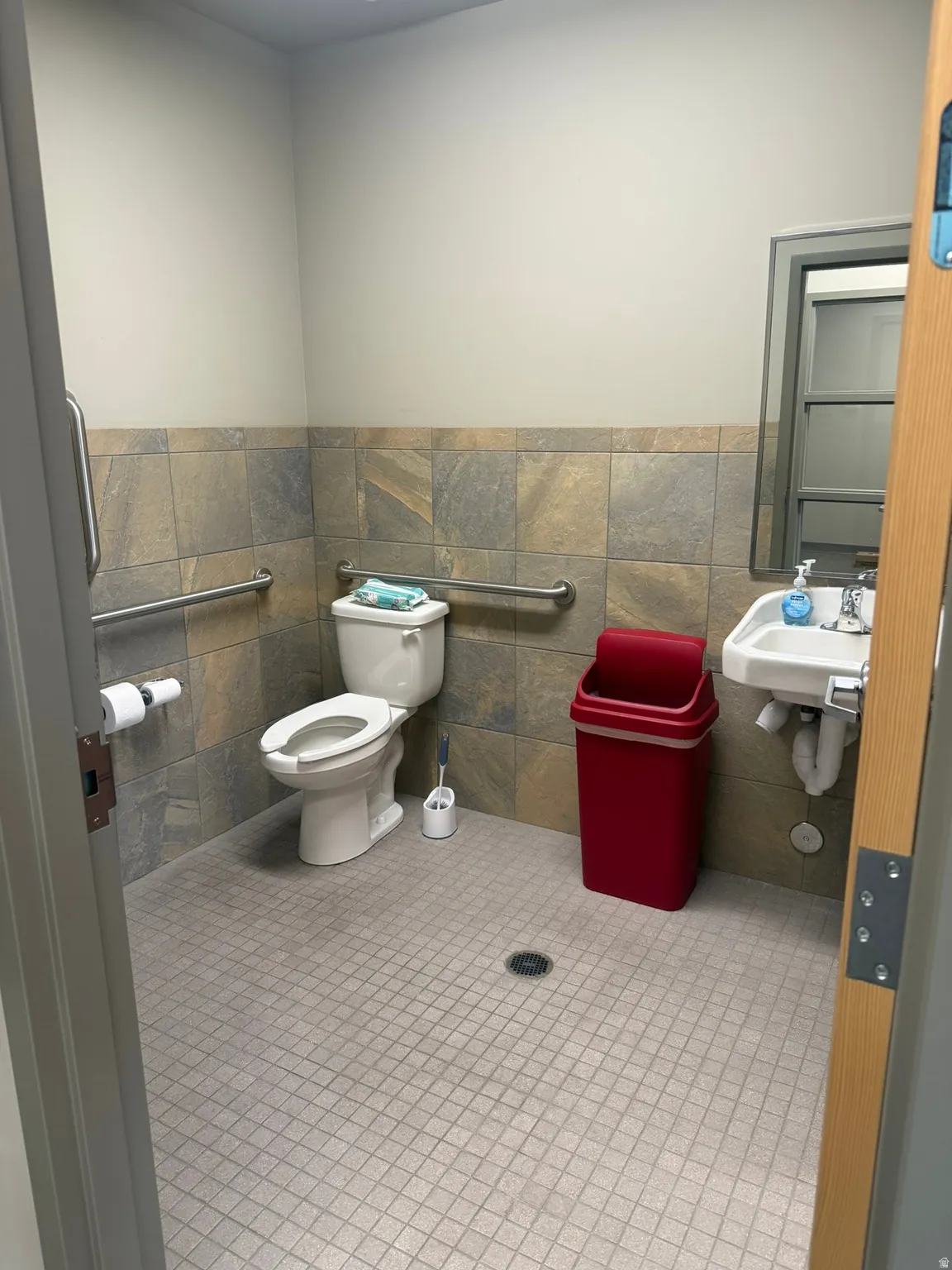 Bathroom with tile walls, light tile patterned floors, and wainscoting