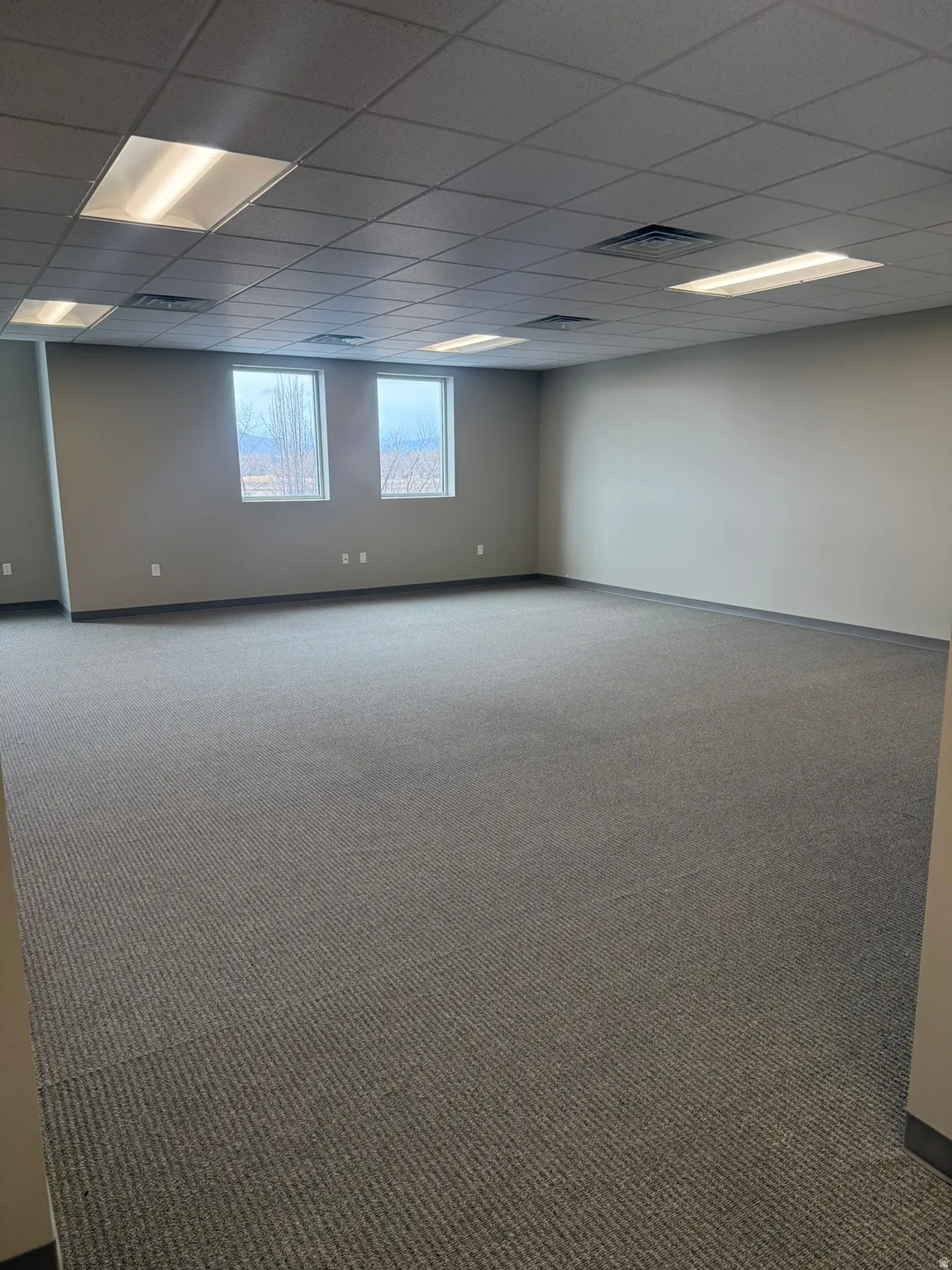 Empty room featuring a drop ceiling and carpet