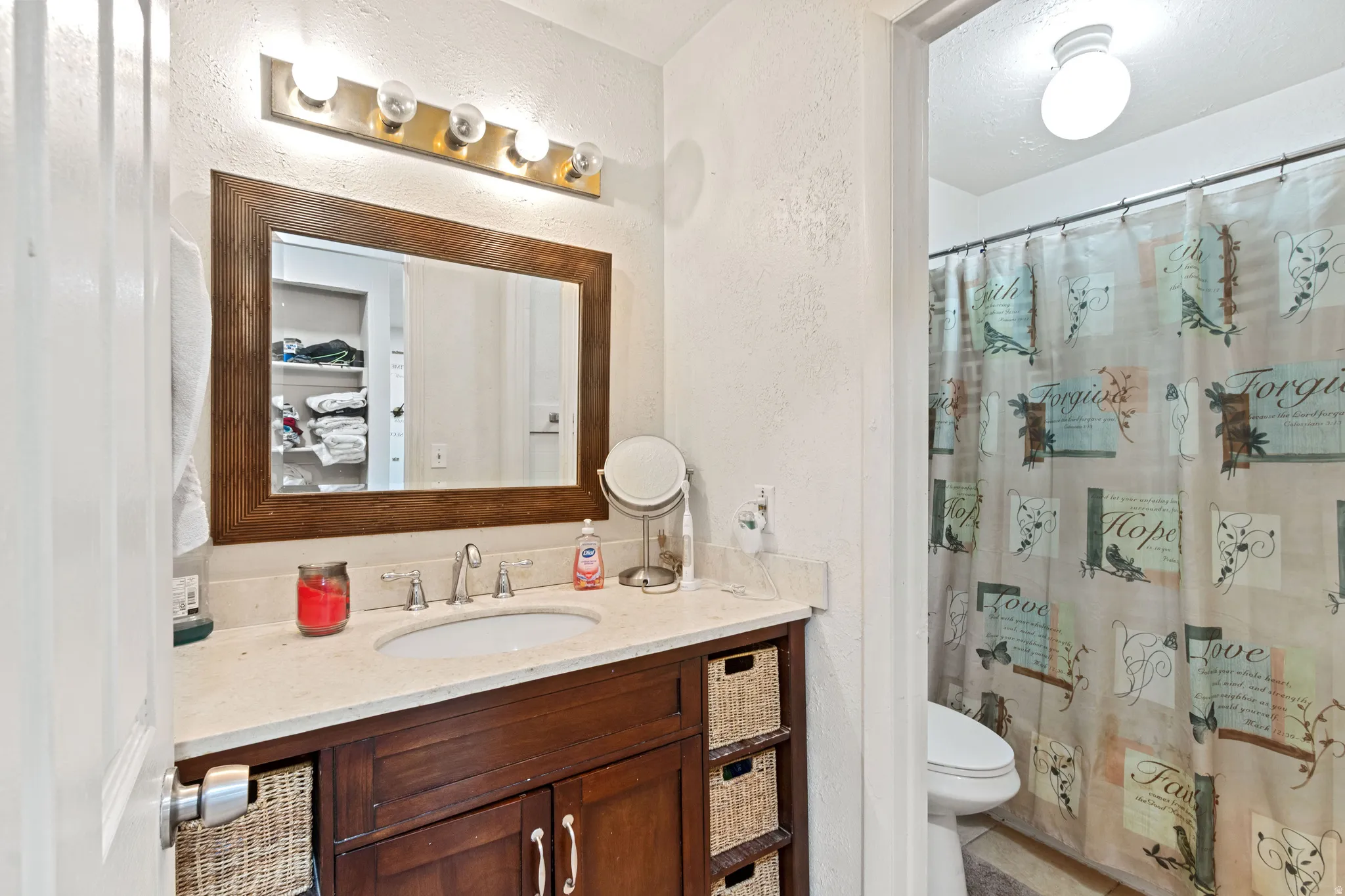 Full bath with a textured wall, vanity, a shower with curtain, and light tile patterned flooring