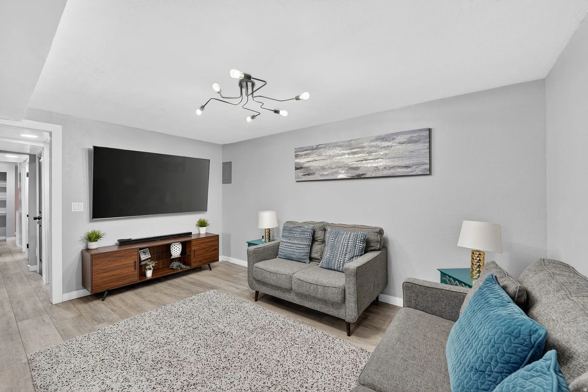 Living room with light wood-style flooring and hanging lights