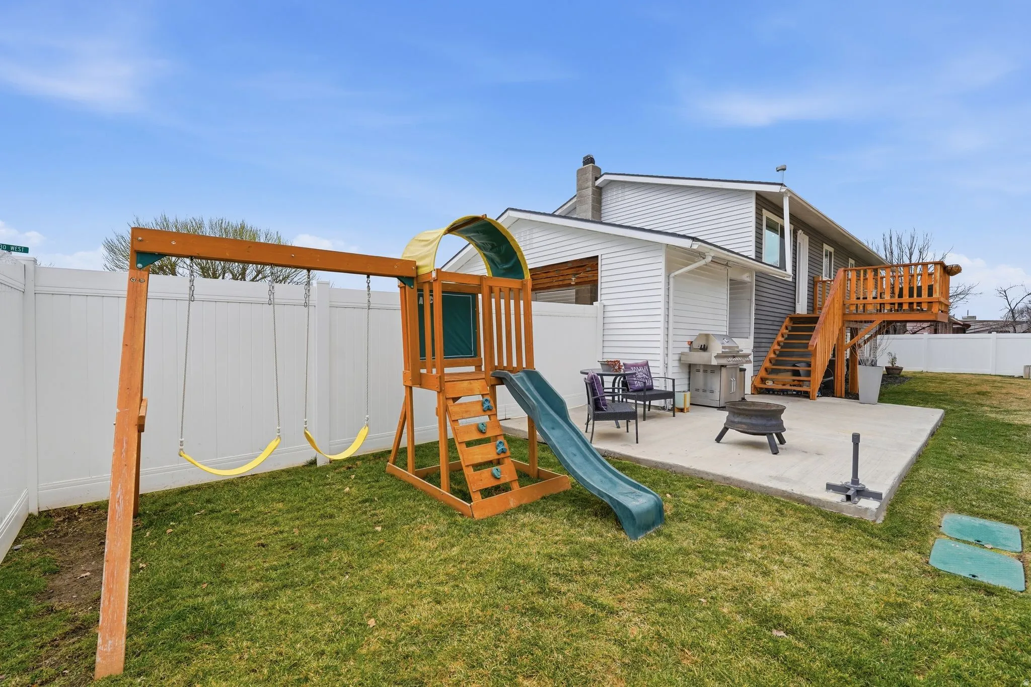 View of jungle gym featuring a patio area, a fenced backyard, and an outdoor fire pit