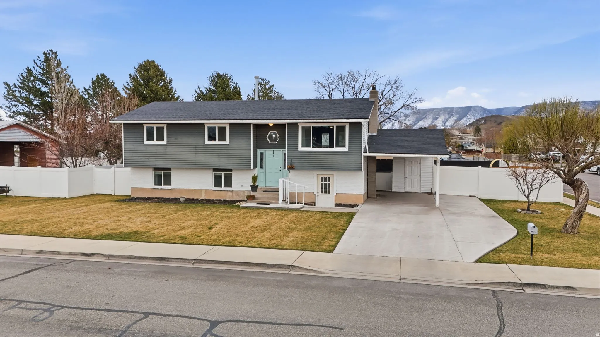 Bi-level home with an attached carport, concrete driveway, a chimney, and a mountain view