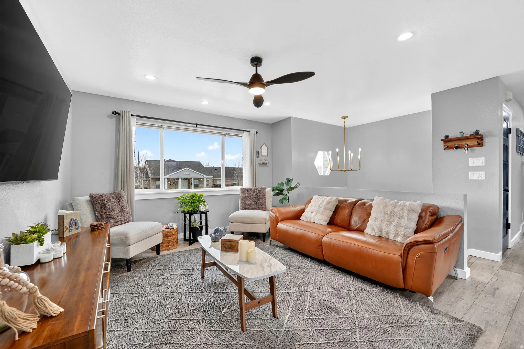 Living area with a ceiling fan, a chandelier, and wood finished floors