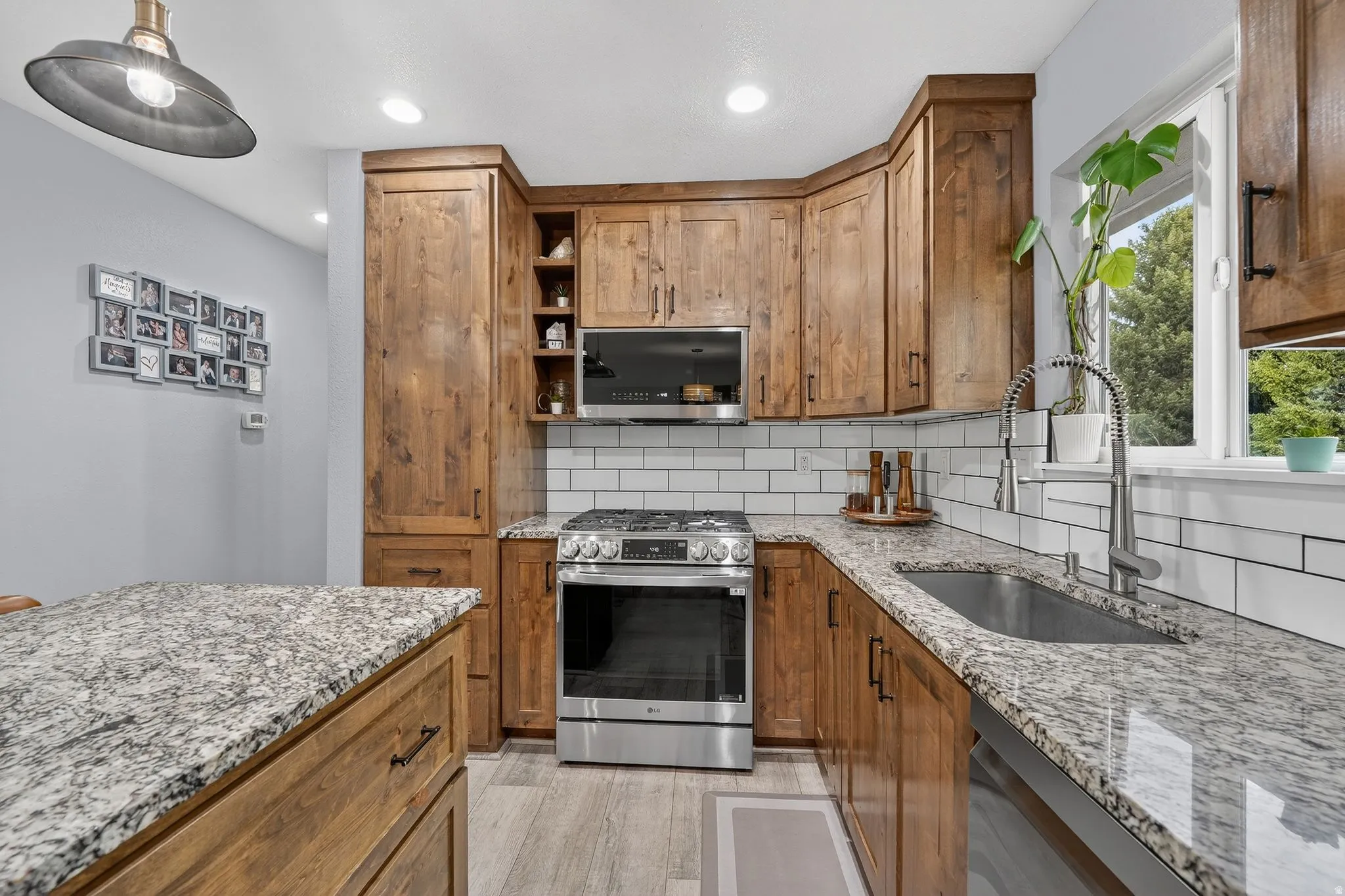 Kitchen featuring open shelves, wood finish cabinetry, stainless steel appliances, and light stone countertops