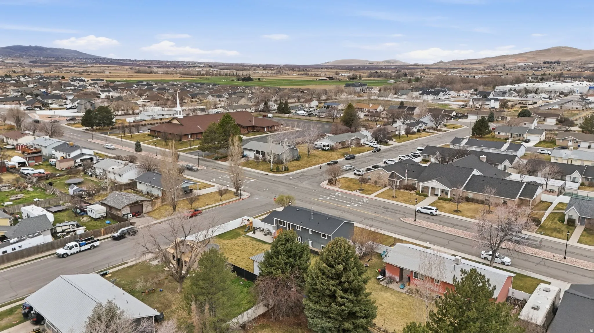 Aerial view of property and surrounding area featuring a mountain backdrop and nearby suburban area