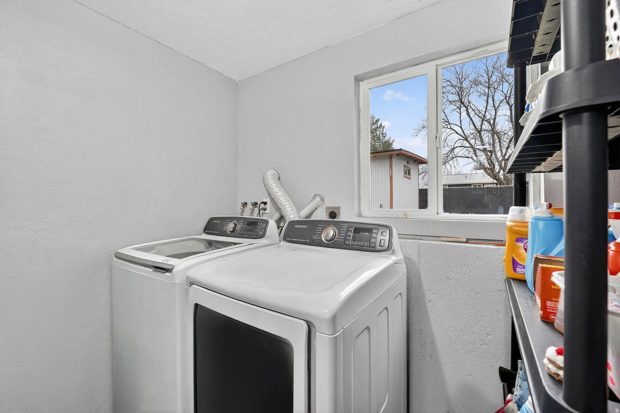 Laundry area with a textured wall and washer and dryer