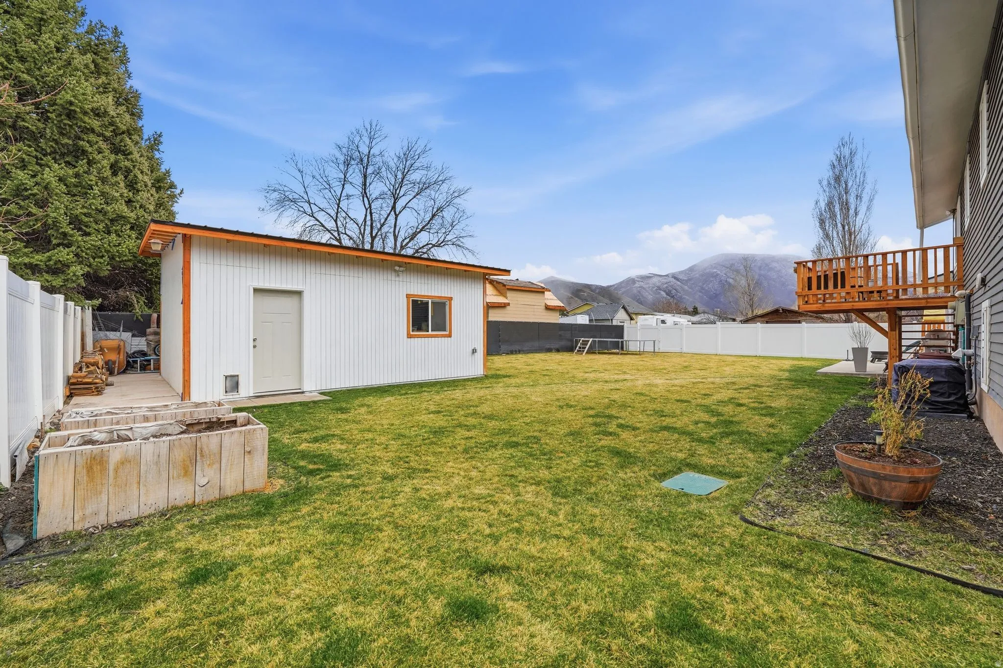Fenced backyard with a mountain view, an outbuilding, and a patio